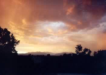 Misty kind of red orange sunset with a dark for ground outline of the trees and bushs and mountains in the back ground.